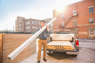 Caucasian worker carrying wood at construction site