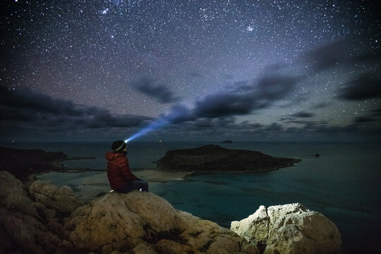 woman with headlamp watching starry night sky at a beautiful lag
