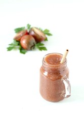 Black tomato smoothie in a glass jar with bamboo straws on a white background