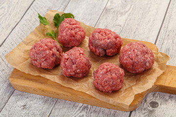 Raw meatball over wooden background