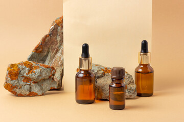 An amber bottle for essential oils and cosmetics stands next to the stone. Glass bottle. Dropper,...