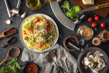 Italian dinner with pasta on ceramic plate with ingredients around on black background. Flat view. Top view.
