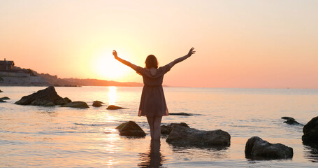 Fototapeta premium Young woman in dress relaxing on the summer beach during beautiful sunrise 