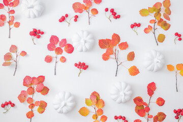 Flat lay pattern with colorful autumn leaves, pumpkins and red berries on a white background