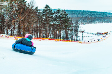 parent with kid sliding down by snowed hill with snowing tube © phpetrunina14