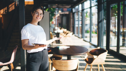 Positive young hostess inviting guests to cafe