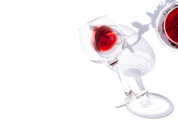 A glass of red wine on the white table with leaves shadows modern composition. Copy space	