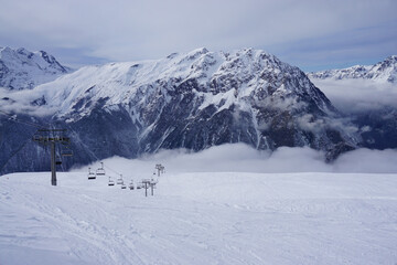 Fototapeta premium chair lift in a ski resort in the mountains of the French Alps with fog lifting
