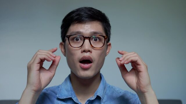 shot of young asian man surprised after putting new eyeglasses with new vision eyesight for eye care and people lifestyle concept