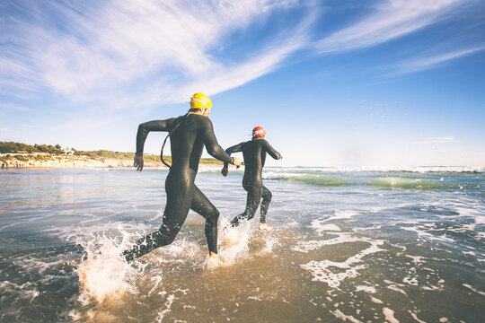 Two triathletes running to the water on triathlon race.