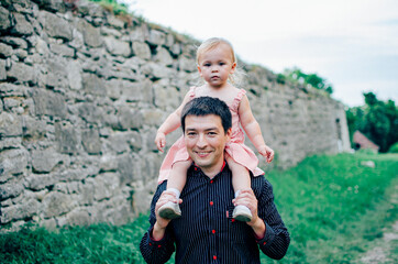 Happy smiling young father with a little cute daughter in pink dress