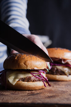 Knife cutting through a quarter pound burger with cheese.