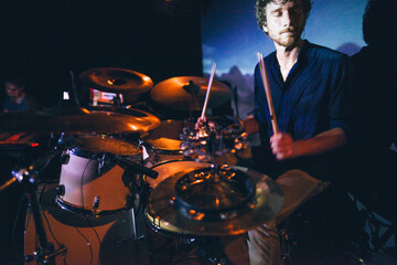 Male musicain playing drums at an underground rock concert