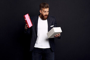 Portrait of a surprised bearded man in a suit who opens a gift from his girlfriend
