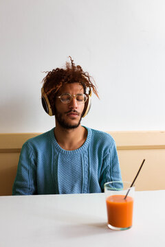 The guy in blue is feeling things, sitting on a bar with headphones on