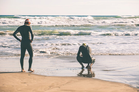 Two triathletes with wetsuit resting after triathlon race.