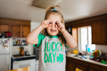 Toddler child in Lucky Day Saint Patrick's Day shirt in kitchen.