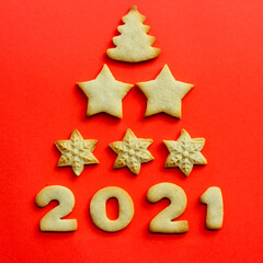 Fototapeta na wymiar Concept for 2021. Greeting Christmas card made of cookies on a red background. cookies christmas tree shape. Top view