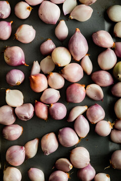 Whole peeled shallots in baking tray ready for cooking.