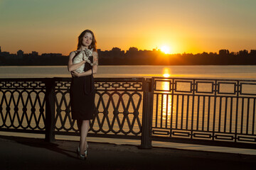Girl with a cat at sunset in the city by the river.