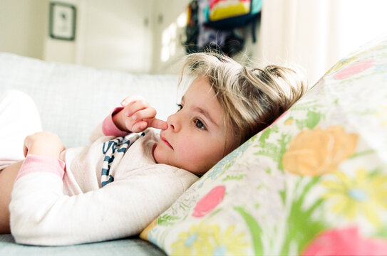 little girl picks nose on couch