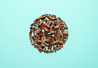 Chocolate pieces in a circle on a blue background. Chocolate curls top view