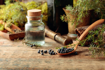 Juniper tincture and juniper berries on an old wooden table.
