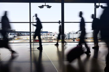 Silhouettes of air travelers navigating the terminal to board airplane flights amid pandemic.