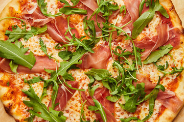 Delicious Italian Pizza with Parma ham and arugula, mozzarella cheese on dark background