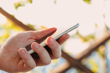 close-up shot of male hands holding smartphone with blank screen copy space for your text message or information content, against green nature background