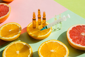 High dose vitamin C, ampule for injection with syringe and fresh juicy orange fruit slides. Concept...