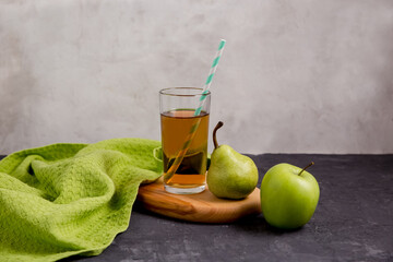 Pear juice in a glass glass, pear and apple on a gray background. copy space