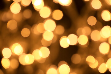 Obraz premium Christmas and Happy New Year on blurred bokeh of gold color on black background, glowing sparks, holiday lights, place for text