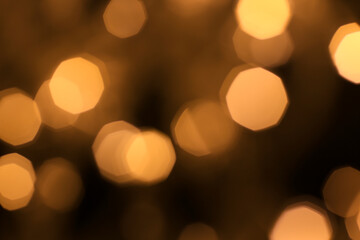 Fototapeta premium Christmas and Happy New Year on blurred bokeh of gold color on black background, glowing sparks, holiday lights, place for text