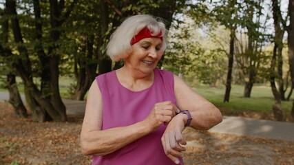 Senior sport runner woman using smart watch, tapping touchscreen, tracking distance, checking pulse