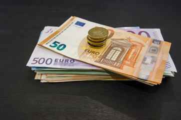 money stack and coins on a black wooden background. Euro banknotes. Much money.