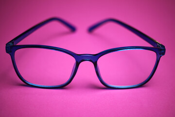 View on isolated eyeglass frame with pink background (focus on frame center)