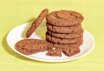 Chocolate oatmeal cookies on a white plate with a yellow background homemade baking concept