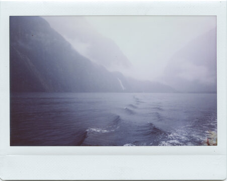 instant photo of ocean waves next to mountains