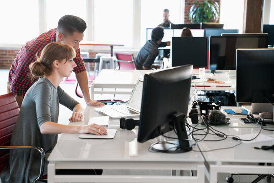 Two business associates looking at computer monitors and talking