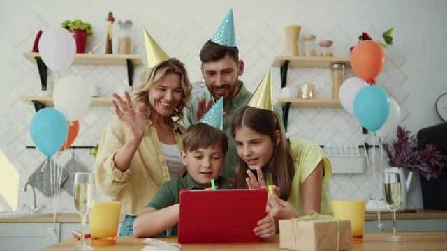 Home party. Family celebration. Young caucasian parents with two kids talking to grandparents congratulating sharing birthday wishes. Holiday at home. Social distance.