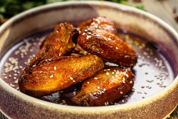 Baked chicken wings in sauce and sprinkled with sesame seeds are on a plate