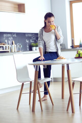 Young woman with orange juice and tablet in kitchen.