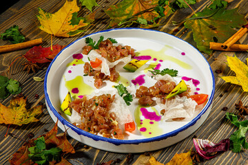 Beef tartare with rice chips and vegetables is on the plate