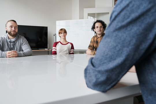 Three young casual business people listening to speaker in a mee