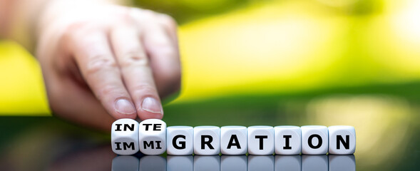 Hand turns dice and changes the word "immigration" to "integration".