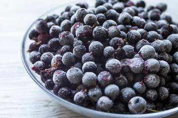 Frozen gooseberries and black currants with rime in a transparent plate