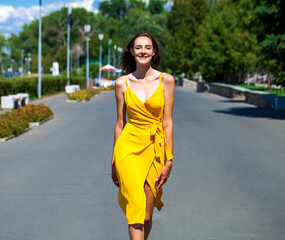 Beautiful brunette posing in a yellow dress, summer outdoor