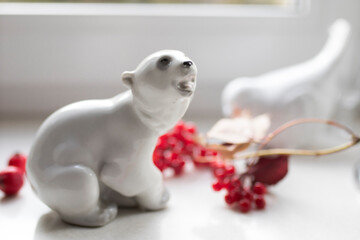 A porcelain figurine of a polar bear with a viburnum branch on the windowsill. Photo for Instagram