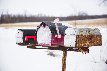 Image of a trio of snow covered worn and textured mailboxes